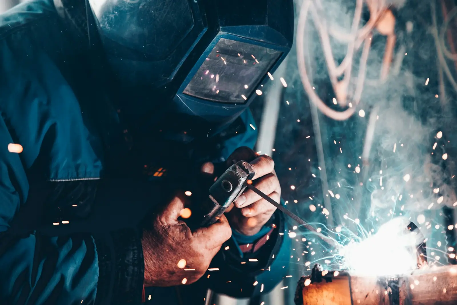 Lasser met lashelm aan het werk tijdens booglassen in een industriële werkplaats