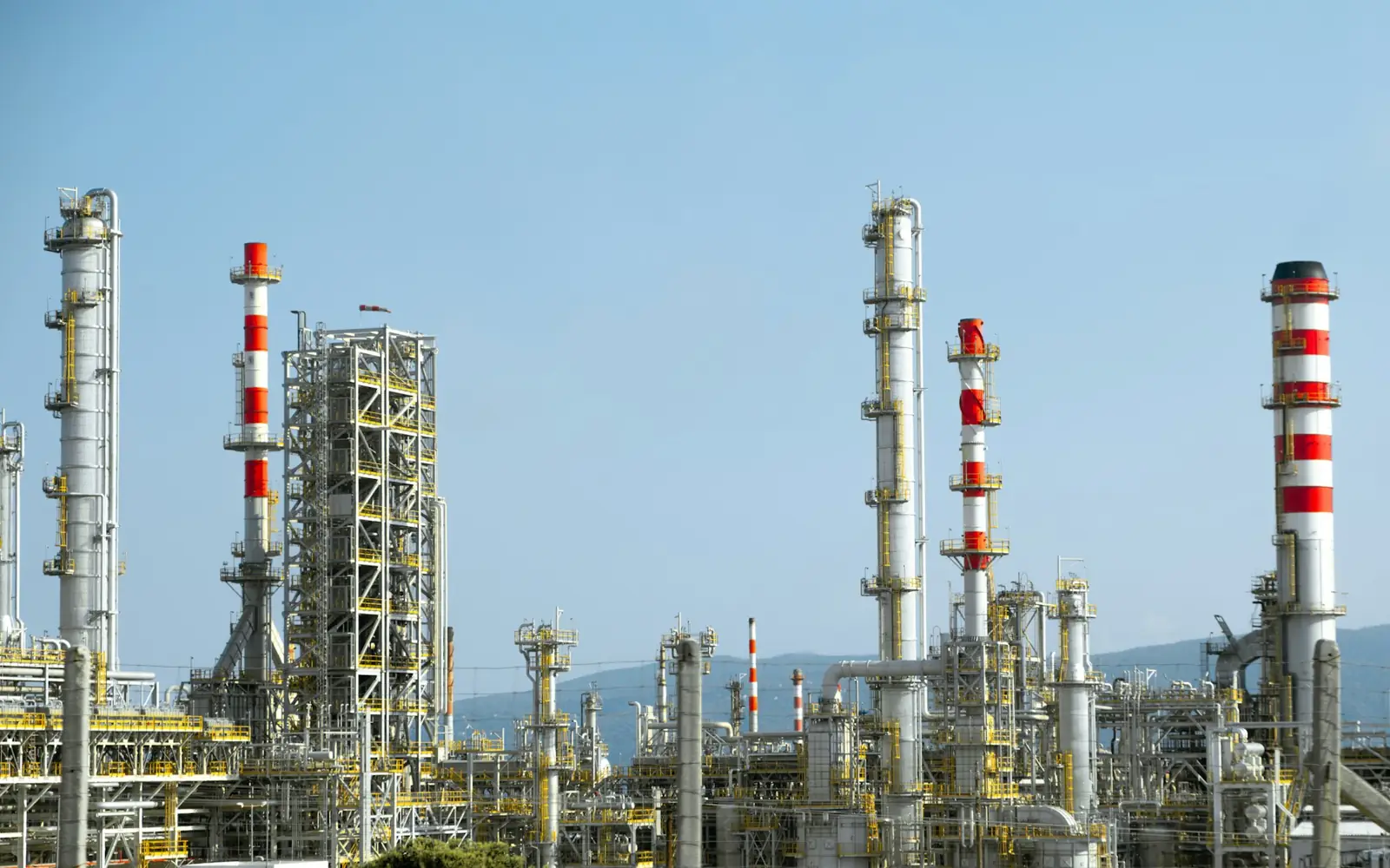Raffinaderij met rood-witte schoorstenen en procesinstallaties, voorbeeld van de petrochemische sector